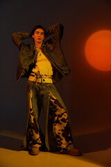 Fashionable non-binary individual expresses vibrant identity against a sunset backdrop