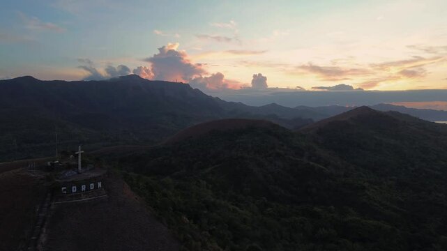 Wide aerial panorama of Mount Tapyas and surrounding Coron hills at sunrise with the summit cross and layered ridges in Palawan