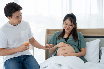 Obraz premium A couple shares a tender moment, the pregnant woman radiating happiness as her partner offers her refreshment, sharing a tender moment of anticipation. Pregnancy Happiness. Childbirth Joy Concept