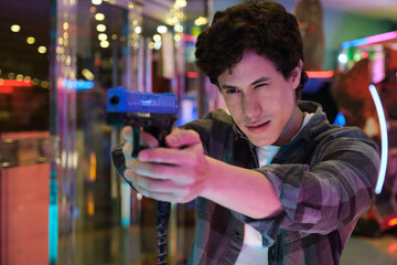 Concentrated gamer playing and aiming with a toy gun in an arcade