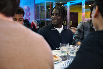 Young people sharing a meal and drinks at a bowling alley restaurant, enjoying their time together