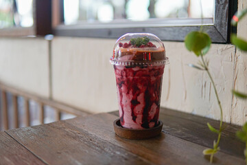 Glass of Blueberry Smoothie on wooden table at cafe.