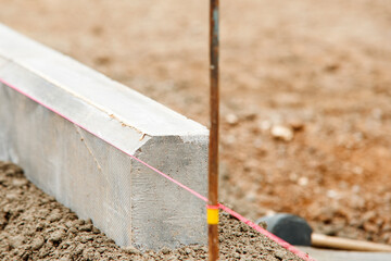 Close-up of builder hands laying new chamfer kerb on semy-dry concrete mix during new residential road construction