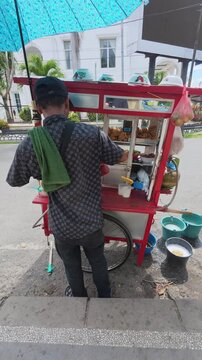 Man With a Food Cart on Sidewalk