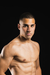 Fototapeta premium Athletic young man proudly showing off his fit physique against black background. Lifestyle. Sport.