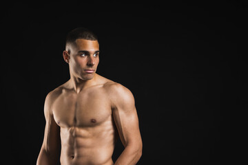 Fototapeta premium Shirtless fit man looking sideways with defined abs against black background. Lifestyle. Sport.