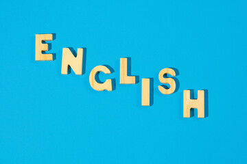 Word English made of wooden letters on a blue background. Banner for advertising learning English or a conversation club.