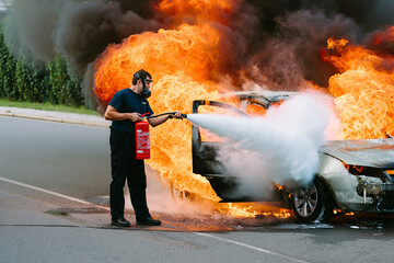A man uses a fire extinguisher to put out a car fire on the side of a road.