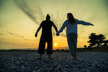 Fototapeta premium Couple enjoying sunset on rocky beach