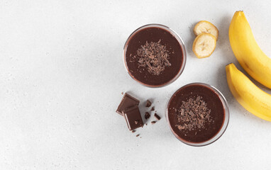 Glass of smoothie with chocolate and banana on white background. Top view. Copy space. Dessert.