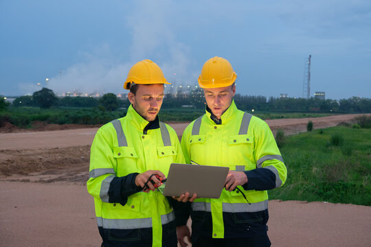 Construction workers discussing project details outdoors at twilight near a building site - Powered by Adobe