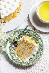 Birthday sour cream and honey cake made of thin layers, decorated with almond petals and candles.