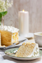 Birthday sour cream and honey cake made of thin layers, decorated with almond petals and candles.