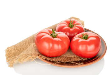 Three pink tomatoes with a jute napkin on a clay plate, close-up, isolated on a white background.