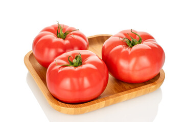 Three pink tomatoes on a bamboo tray, close-up, isolated on a white background.