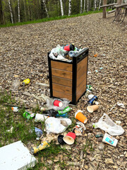 Overflowing Trash Bin in Park with Litter on Ground. Made with a smartphone