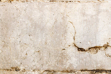 Textured beige wall surface with cracks and imperfections showcasing natural stone material and rustic charm