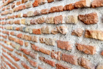 Textured brick wall with varying shades of red and brown, showcasing rustic charm and architectural detail