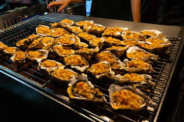 Street food at a night market in Sanya, Hainan Island in China.. Grill oyster in the street market
