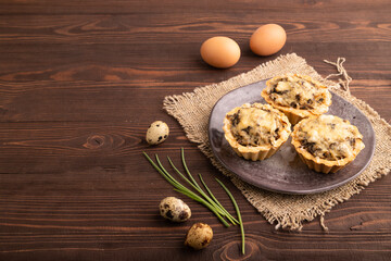 Tartlets with meat and cheese on brown wooden, linen textile. side view, copy space
