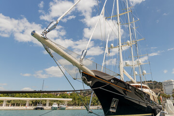 Majestic sailing ship docked at marina under bright blue sky, showcasing intricate rigging and...