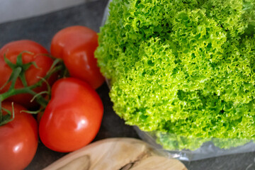 Fresh tomatoes and salad on a wooden board with a marble kitchen countertop. Perfect for healthy eating, vegetables, vitamins, organic food ads, and kitchen recipe visuals.