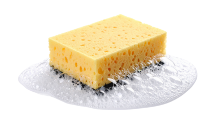 A yellow cleaning sponge with visible pores sits on a layer of white soap suds.