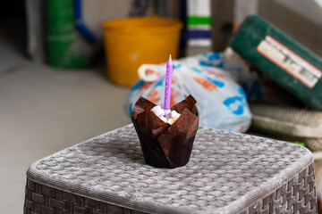 A delicious cupcake adorned with a vibrant purple candle sitting on top of it