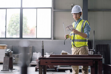 Asian male engineers inspect metal workpieces in the workshop.