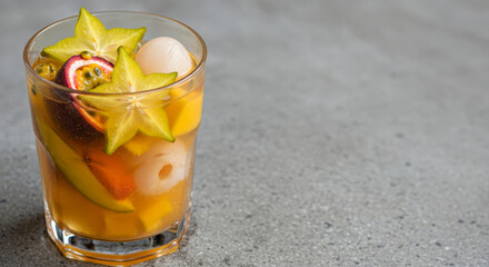 Colorful tropical fruit cocktail in glass with exotic fruits. Neutral background with copy space for design use.