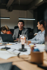 A group of business people engaged in a discussion at a dimly lit office. They are working diligently on laptops and documents, emphasizing teamwork and dedication in a late-night setting.