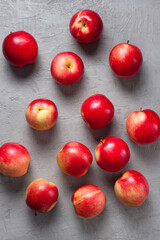 Red apples are randomly scattered across a light gray concrete textured surface, creating a composition perfect for healthy food themes, rustic kitchen visuals, or seasonal promotions.