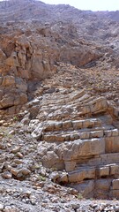Curved strata stack above rugged field, curved strata undulate under dusty light, curved strata...