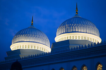 Obraz premium Twilight view of illuminated mosque domes with crescent finial