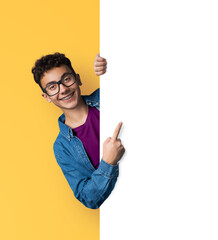 Young man wear eye glasses, braces, peep from blank empty banner mockup sign board signboard, advertise pointing area for sales slogan text isolate orange yellow background. Dental care ad
