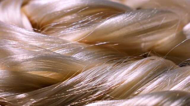 Macro detail of smooth, bundled, cream colored yarns, showing the fiber texture in soft light, useful for backgrounds.
