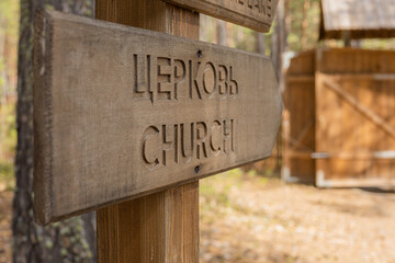 Wooden directional arrow with the word church written in English and Russian, wooden structure in...