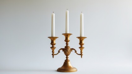 Three-candle vintage brass candelabrum set against a white backdrop