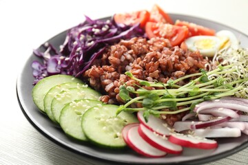 Tasty salad with brown rice on white wooden table, closeup
