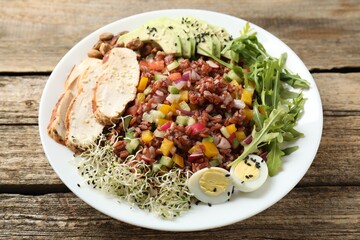 Tasty salad with brown rice on wooden table, closeup