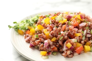 Tasty salad with brown rice on white marble table, closeup