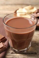 Tasty chocolate milk, pieces and banana on wooden table, closeup