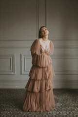Elegant woman in a pink tiered tulle gown posing against a neutral background