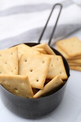 Tasty salty crackers on white tiled table, closeup