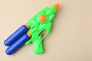 Bright plastic water gun on beige background, top view. Space for text