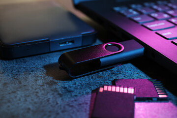 SD memory cards, USB flash drive, hard disk drive and laptop on dark grey table, closeup