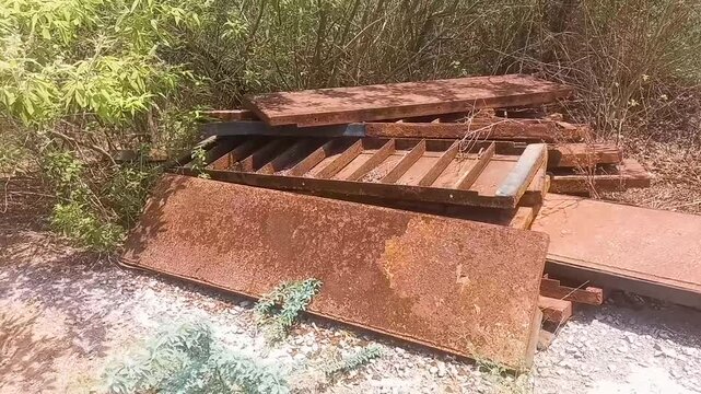 Weathered steel sheets scattered amidst natural foliage hint at the raw essence of industry, showcasing the beauty of rust and the passage of time.