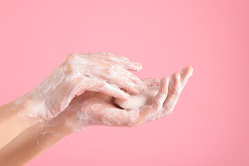 Woman washing hands with soap on light pink background, closeup