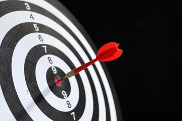 Targeting. Dart board with arrow on black background, closeup