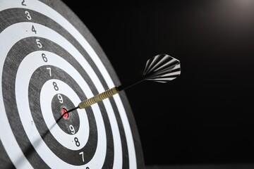 Targeting. Dart board with arrow on dark background, closeup